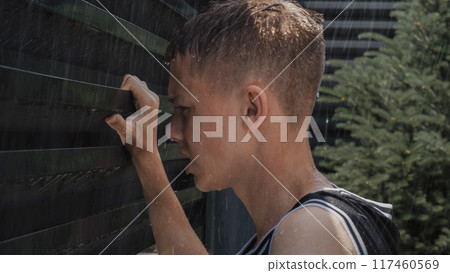 Tired and upset teenager breathing heavily and holding hands on the iron fence Tired and upset teenager breathing heavily and holding hands on the iron fence 117460569