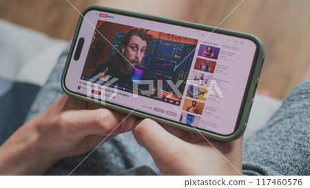 Caucasian boy watches video of blogger about stock trading using phone 117460576