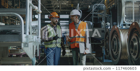 Two engineers discuss work process walking at manufacturing facility 117460603