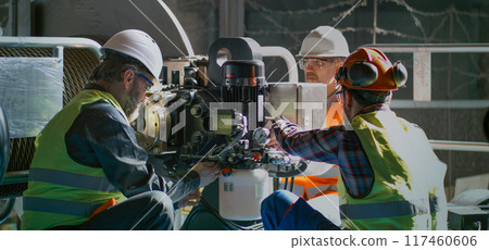 Male technicians discuss production and inspect industrial equipment 117460606