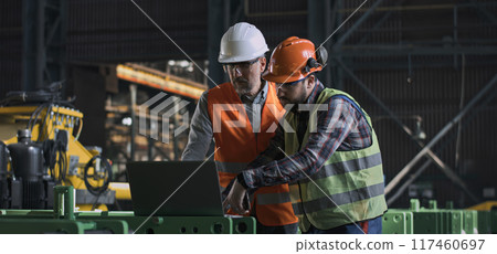 Two heavy industry engineers work using laptop and mobile phone at factory 117460697