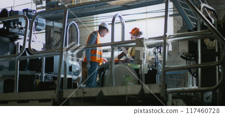 Male worker discusses production and equipment with mature supervisor Male worker discusses production and equipment with mature supervisor 117460728