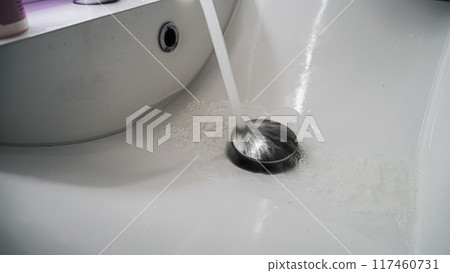 Clean bathroom sink with water pouring down on chrome stopper Clean bathroom sink with water pouring down on chrome stopper 117460731
