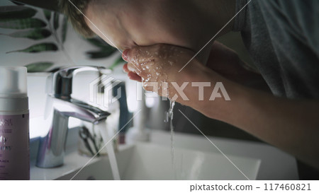 Boy washes face with cold water and wipes hands using towel Boy washes face with cold water and wipes hands using towel 117460821