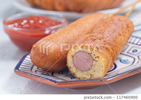 Corn dogs on white blue plate, served with ketchup, horizontal closeup Corn dogs on white blue plate, served with ketchup, horizontal closeup 117460900