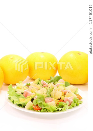 Pomelo, prosciutto and avocado salad with large citrus fruits on a light background 117461013