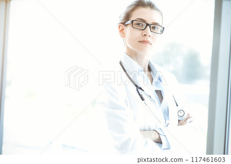 Beautiful woman doctor with stethoscope smiling charmingly and ready to help patients in sunny hospital. Medicine concept 117461603