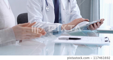 Doctor is consulting patient in modern clinic. Healthcare professional discusses medical information with a woman, using a tablet computer. Medicine concept Doctor is consulting patient in modern clinic. Healthcare professional discusses medical information with a woman, using a tablet computer. Medicine concept 117461692