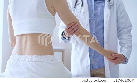Doctor man examines a patient's elbow during a medical consultat Doctor man examines a patient's elbow during a medical consultat 117461807