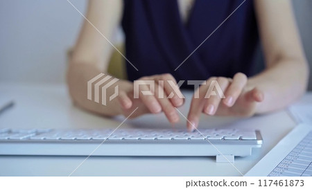 Businesswoman with dark blue blues blues is working on a computer keyboard in the office. Business concept Businesswoman with dark blue blues blues is working on a computer keyboard in the office. Business concept 117461873