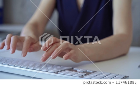 Businesswoman with dark blue blues blues is working on a computer keyboard in the office. Business concept Businesswoman with dark blue blues blues is working on a computer keyboard in the office. Business concept 117461883