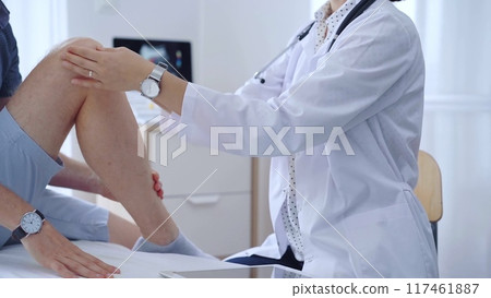 Doctor is carefully examining a patient's knee, providing personalized care and support. Medicine and orthopedic concept Doctor is carefully examining a patient's knee, providing personalized care and support. Medicine and orthopedic concept 117461887