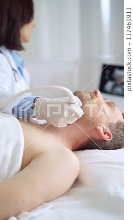 Doctor performing neck ultrasound exam on male patient Doctor performing neck ultrasound exam on male patient 117461911