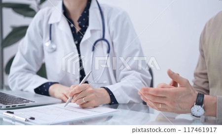 Doctor and patient are talking in clinic after health check up. Female physician is making notes. Medicine concept 117461917
