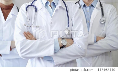 Group of doctors wearing white coats and stethoscopes standing with arms crossed. Medical team at work 117462110