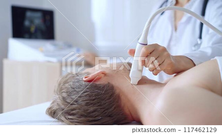 Doctor woman performing neck ultrasound exam on male patient. Medicine service concept. Thyroid gland health 117462129