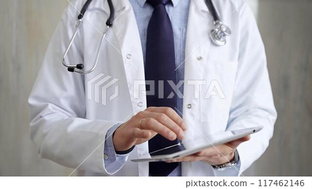 Doctor man wearing lab coat and stethoscope using tablet computer in hospital. Medicine and science 117462146
