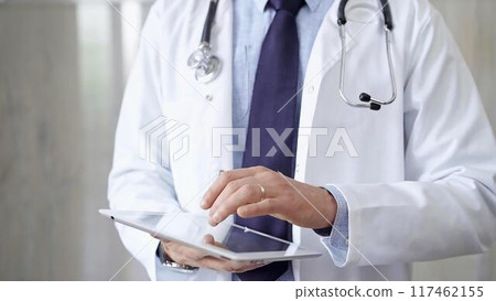 Doctor man wearing lab coat and stethoscope using tablet computer in hospital. Medicine and science Doctor man wearing lab coat and stethoscope using tablet computer in hospital. Medicine and science 117462155