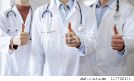Group of doctors are are standing and showing thumbs up in hospital corridor. Medicine excellent service Group of doctors are are standing and showing thumbs up in hospital corridor. Medicine excellent service 117462161