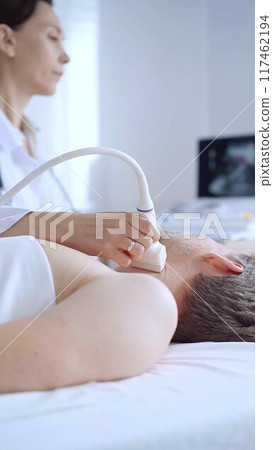 Doctor woman performing neck ultrasound exam on male patient. Medicine service concept Doctor woman performing neck ultrasound exam on male patient. Medicine service concept 117462194