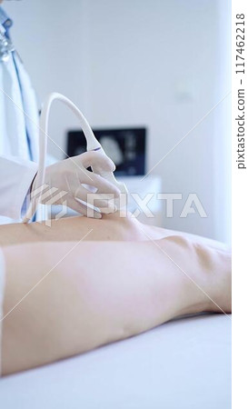 Male doctor with white medical gloves using ultrasound equipment on the knee of a female patient. The results on a monitor in the background. Medicine concept 117462218