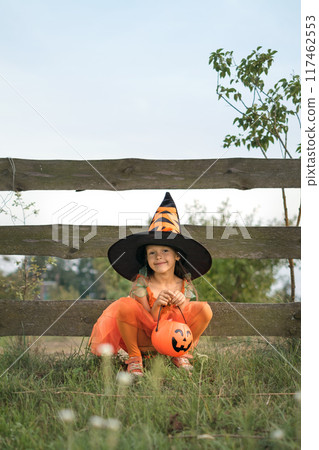 A funny adorable little girl dressed up in a Halloween costume and hat 117462553