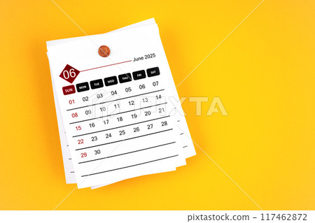 June 2025 calendar page with wooden push pin on yellow background. June 2025 calendar page with wooden push pin on yellow background. 117462872