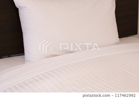 White pillow and comforter on a hotel bed 117462992