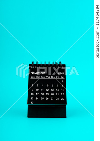 Black Calendar for November 2025. Desktop calendar on a green background. Black Calendar for November 2025. Desktop calendar on a green background. 117464294