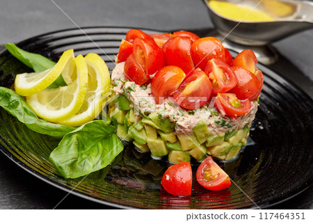 Fresh avocado and tuna salad topped with cherry tomatoes, garnished with lemon slices and basil Fresh avocado and tuna salad topped with cherry tomatoes, garnished with lemon slices and basil 117464351