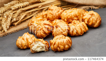 Delicious cream-filled profiteroles, golden and crisp, perfect for a sweet dessert treat Delicious cream-filled profiteroles, golden and crisp, perfect for a sweet dessert treat 117464374