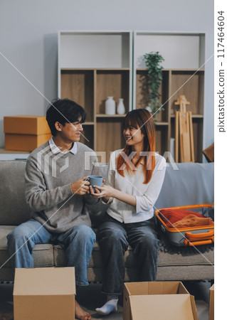 Young Asian couple relocating to a new house, joyfully packing and unpacking belongings. Expertise in moving, packing, togetherness, and creating a new home together. Young Asian couple relocating to a new house, joyfully packing and unpacking belongings. Expertise in moving, packing, togetherness, and creating a new home together. 117464604