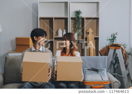 Young Asian couple relocating to a new house, joyfully packing and unpacking belongings. Expertise in moving, packing, togetherness, and creating a new home together. Young Asian couple relocating to a new house, joyfully packing and unpacking belongings. Expertise in moving, packing, togetherness, and creating a new home together. 117464613