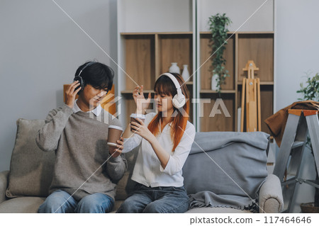 Asian Female discussing new project with male colleague. Young woman talking with young Asian man with financial on sofa in home office Asian Female discussing new project with male colleague. Young woman talking with young Asian man with financial on sofa in home office 117464646