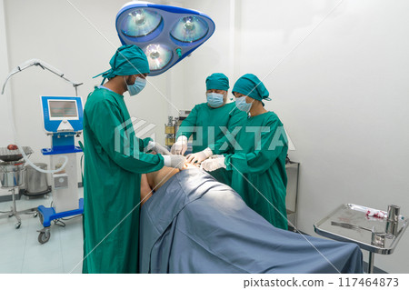 Group of surgeon and nurse in surgical green gown uniform performing surgical operation in operating room. Emergency surgical care concept. Group of surgeon and nurse in surgical green gown uniform performing surgical operation in operating room. Emergency surgical care concept. 117464873