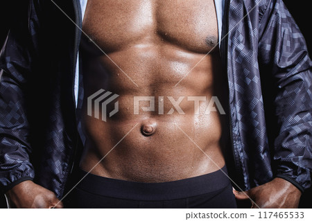 Black man, muscle and abdomen in studio for exercise, strong bodybuilder or training for wellness. Male athlete, dark background and healthy for fitness workout, stomach with abs for gym sport 117465533