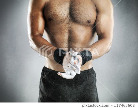 Chalk, hands and bodybuilder in studio for exercise, weightlifting and fitness or gymnastics. Male body, powder and topless for workout, training or muscular on gray background with arm bands 117465608