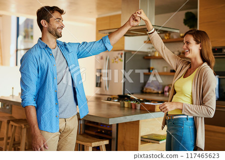Man, woman and dancing together in kitchen for wellness, happiness for anniversary or date. Happy couple, movement and home with hands for support, partners with commitment and peace or smile 117465623