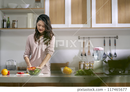 young asian woman preparing meal in kitchen at home 117465677