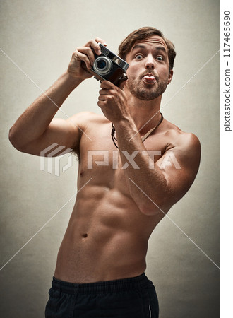 Studio, vintage camera or portrait of man for picture, progress or workout results with confidence. Male bodybuilder, photographer or muscle for wellness, health or tongue out by white background Studio, vintage camera or portrait of man for picture, progress or workout results with confidence. Male bodybuilder, photographer or muscle for wellness, health or tongue out by white background 117465690