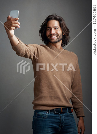 Studio, selfie and man with mobile for profile picture, social media update or memory on dark background. Photography, smile and person with smartphone for happiness, blog post or communication 117465692