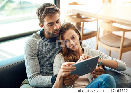 Hug, couple and tablet on sofa for web app, movie selection or streaming choice at home. Thinking, man and woman with tech and love embrace on couch for bonding, search and scrolling tv subscription 117465762