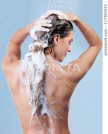 Shower, back view and woman washing hair for shampoo, cosmetics and wellness cleaning or conditioner. Female person, happy and rinsing scalp in studio blue background for skin care or morning routine 117465815