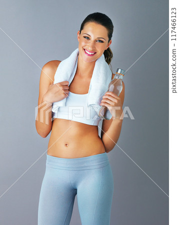 Fitness, portrait and happy woman with water in studio for wellness, detox and workout on grey background. Exercise, gym towel or face of athlete with sports liquid for hydration, nutrition or diet Fitness, portrait and happy woman with water in studio for wellness, detox and workout on grey background. Exercise, gym towel or face of athlete with sports liquid for hydration, nutrition or diet 117466123