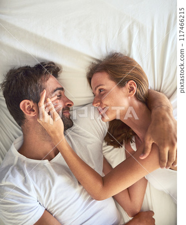 Love, couple and smile to relax on bed above view for bonding, peace or support of marriage commitment at house. Woman, man and touching face for embrace, care or relationship romance on anniversary Love, couple and smile to relax on bed above view for bonding, peace or support of marriage commitment at house. Woman, man and touching face for embrace, care or relationship romance on anniversary 117466215