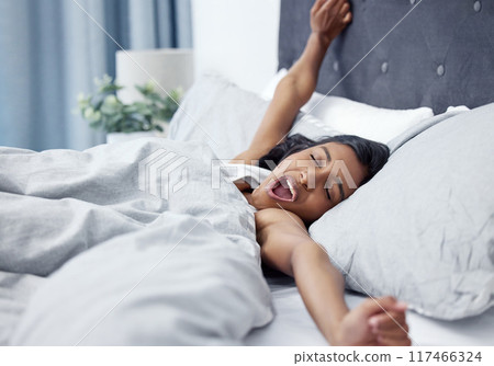 Woman, stretching and yawning in bed at house with pillow for sleeping, comfort and vacation in the morning. Freelancer, wake up and tired with duvet in home for wellness, relax or holiday on weekend Woman, stretching and yawning in bed at house with pillow for sleeping, comfort and vacation in the morning. Freelancer, wake up and tired with duvet in home for wellness, relax or holiday on weekend 117466324