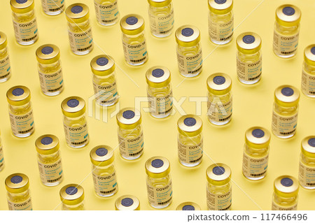 Vials, covid 19 and liquid for healthcare in studio, treatment and bottle for virus on yellow background. Vaccine, medicine and container for immunity or viral influenza, prevention and pandemic Vials, covid 19 and liquid for healthcare in studio, treatment and bottle for virus on yellow background. Vaccine, medicine and container for immunity or viral influenza, prevention and pandemic 117466496