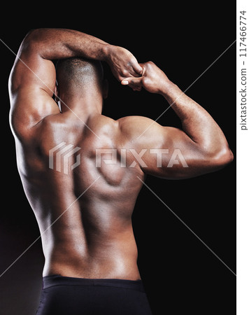 Black man, muscle and stretching arm in studio for wellness, fitness or workout routine on dark background. Back, bodybuilder athlete and person with biceps for strength, toned physique or flexing 117466774