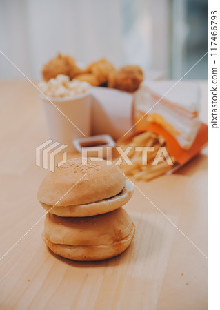 fast food, people and unhealthy eating concept - close up of woman hands holding hamburger or cheeseburger 117466793