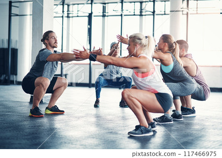 People, personal trainer and squating exercise for fitness in health club, wellness workout and strength for muscles. Challenge, body and balance for core, determination and instructor talking 117466975